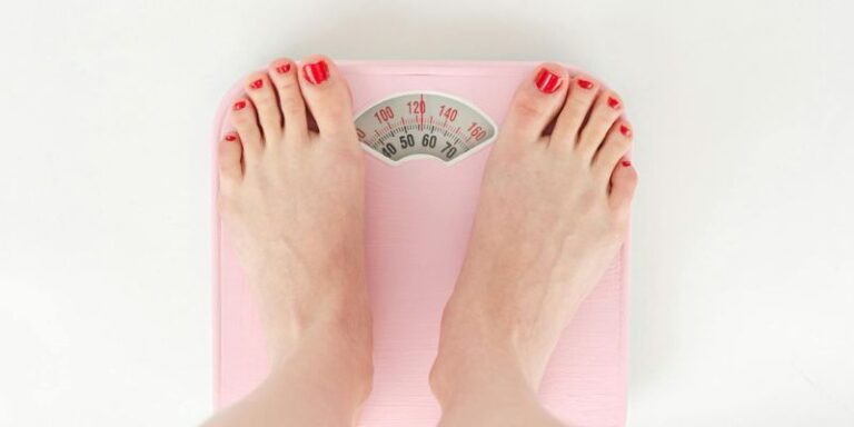 Weight Loss Tips - Woman weighing on scales in studio