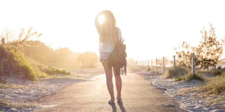 Woman Carrying Backpack Standing On Asphalt Road During Golden Hour