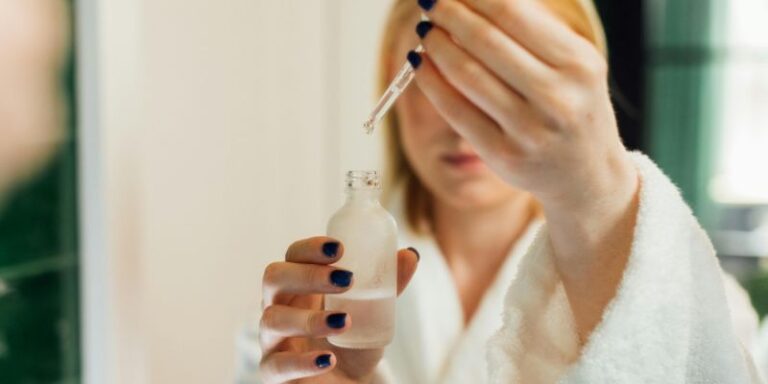 Reflection of a Woman Holding a Bottle of Serum