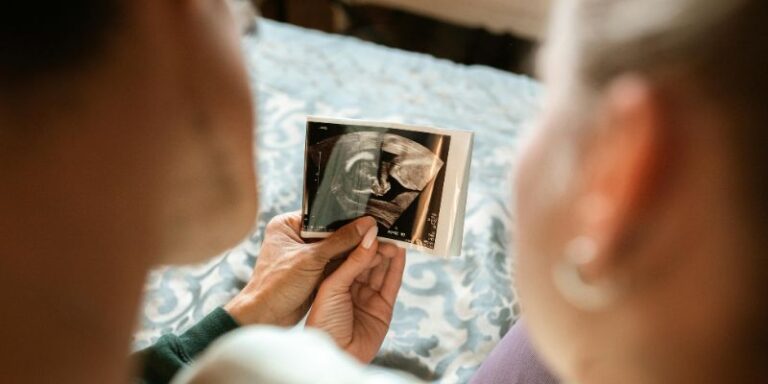 pregnancy - Woman in White Long Sleeve Shirt Holding Photo of Man in Black Suit