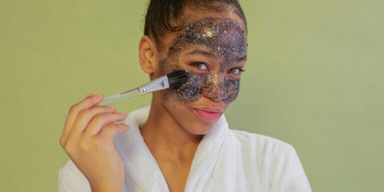 A woman applying sparkling face mask with brush