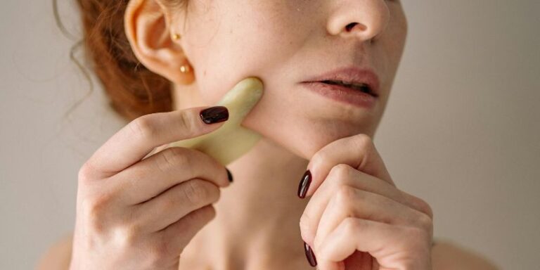 face yoga - Photograph of a Woman Using a Jade Stone on Her Face